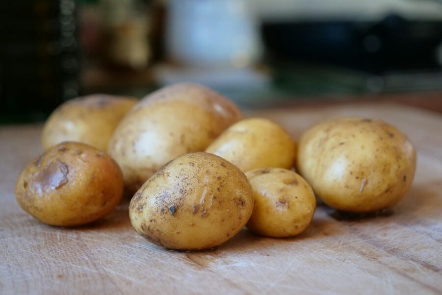 Several raw potatoes resting on a wooden surface