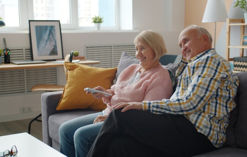 Elderly couple relaxing on a couch watching television