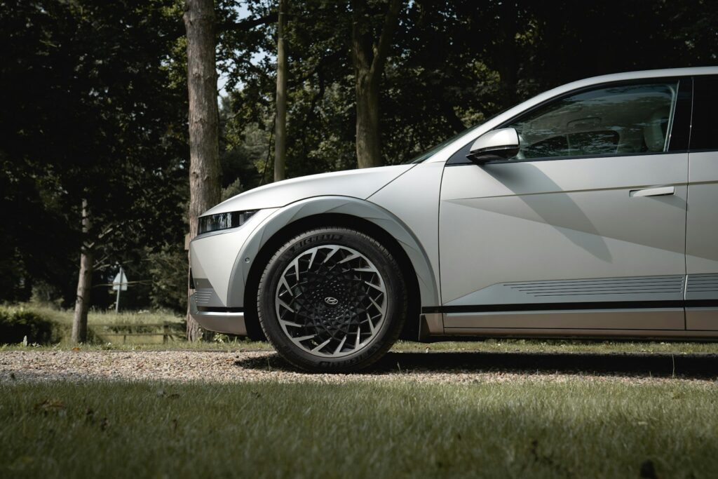 A modern silver car parked on a gravel road.