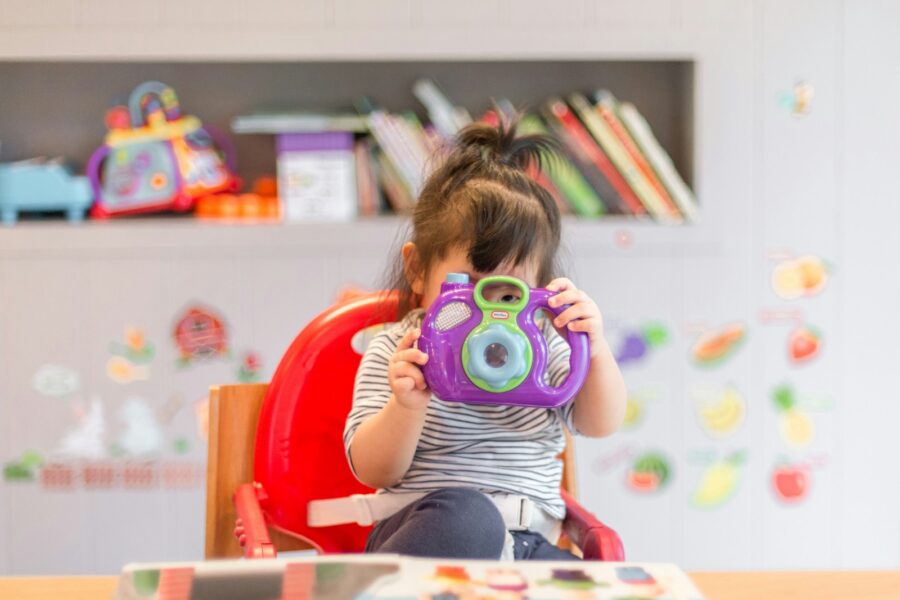 girl holding purple and green camera toy