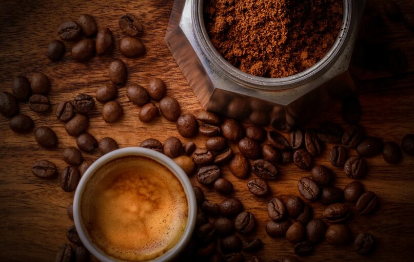 brown coffee beans beside white ceramic mug