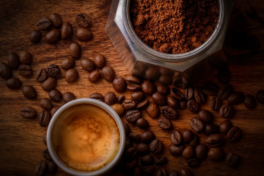 brown coffee beans beside white ceramic mug