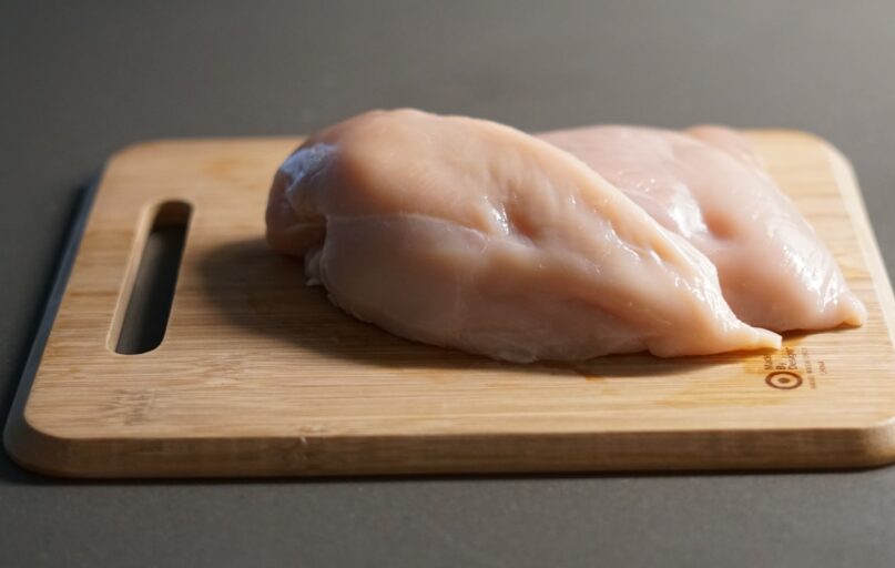 a piece of raw chicken on a cutting board