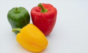 three different colored peppers on a white surface