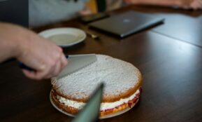 A person cutting a sandwich on a wooden table