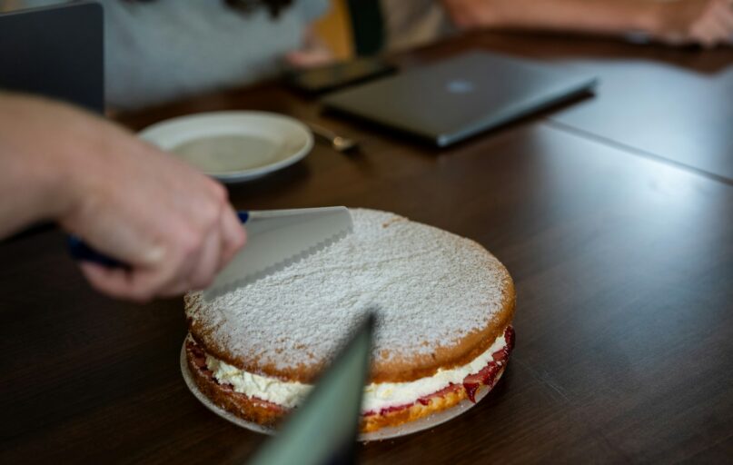 A person cutting a sandwich on a wooden table