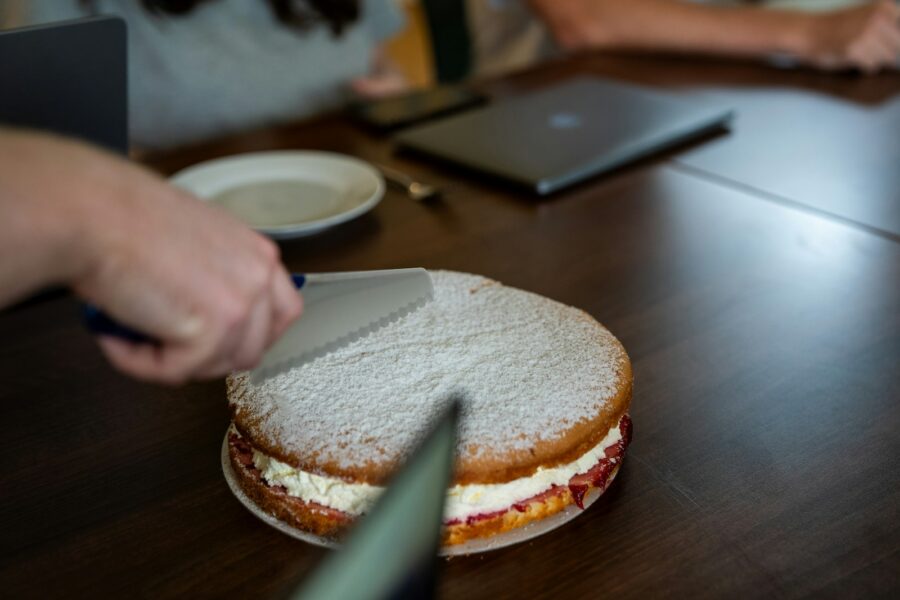 A person cutting a sandwich on a wooden table