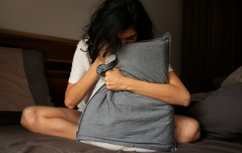 A woman sitting on a bed holding a pillow