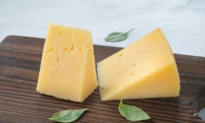 a couple of pieces of cheese sitting on top of a wooden cutting board