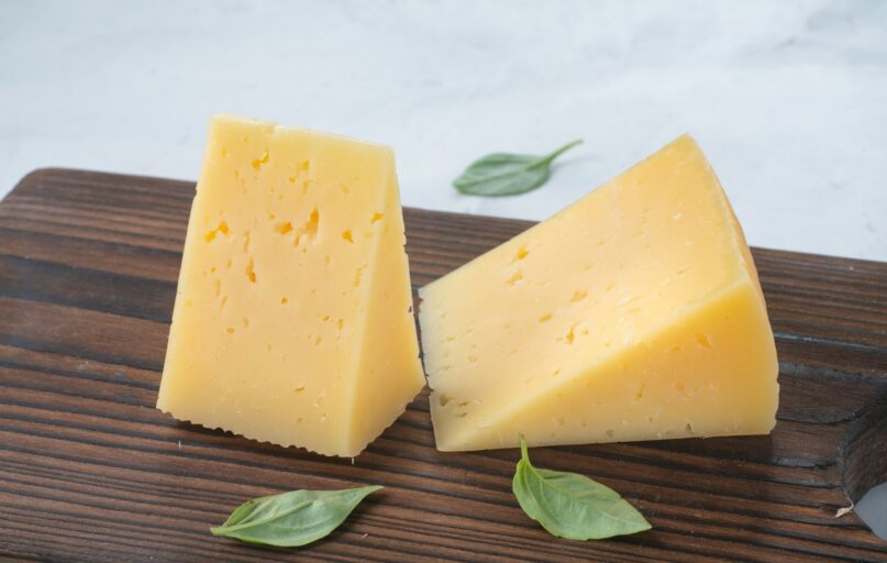 a couple of pieces of cheese sitting on top of a wooden cutting board