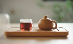 clear glass cup with tea near brown ceramic teapot
