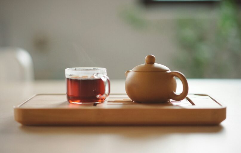 clear glass cup with tea near brown ceramic teapot