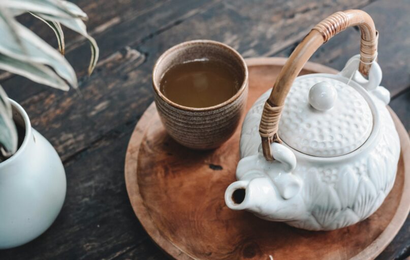 white and brown ceramic teapot on wooden tray