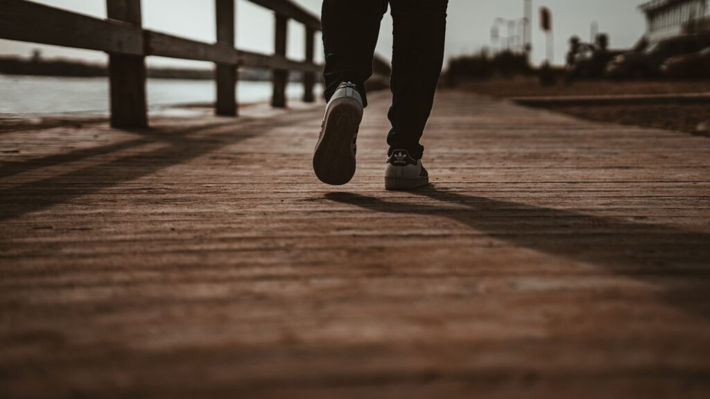 person in black pants and black shoes standing on brown wooden dock during daytime