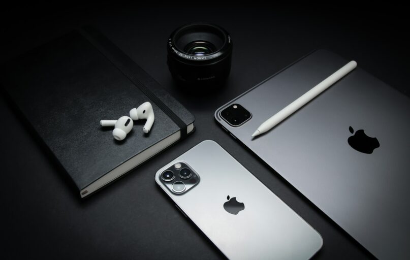 silver macbook beside black camera lens and black camera lens