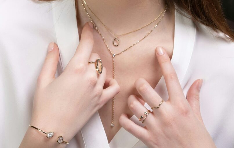 a close up of a person wearing rings and a necklace