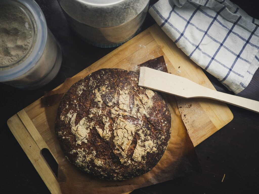 round baked pastry on brown wooden chopping board with wooden spatula