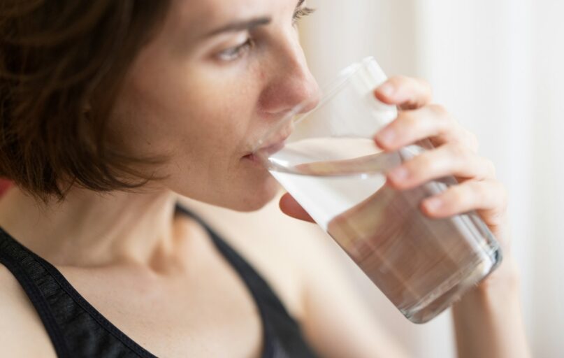 woman in black tank top drinking water