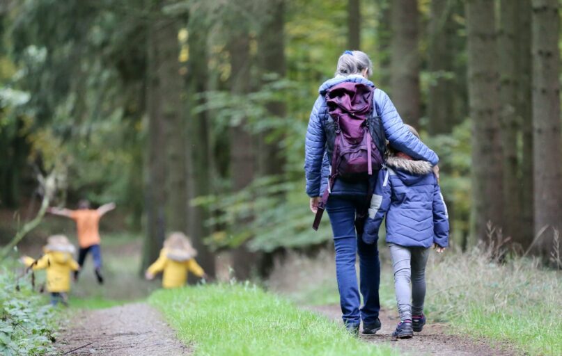 woman in blue denim jeans and black jacket walking with woman in green jacket