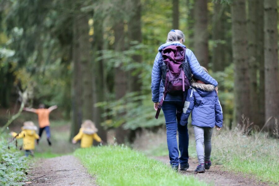 woman in blue denim jeans and black jacket walking with woman in green jacket