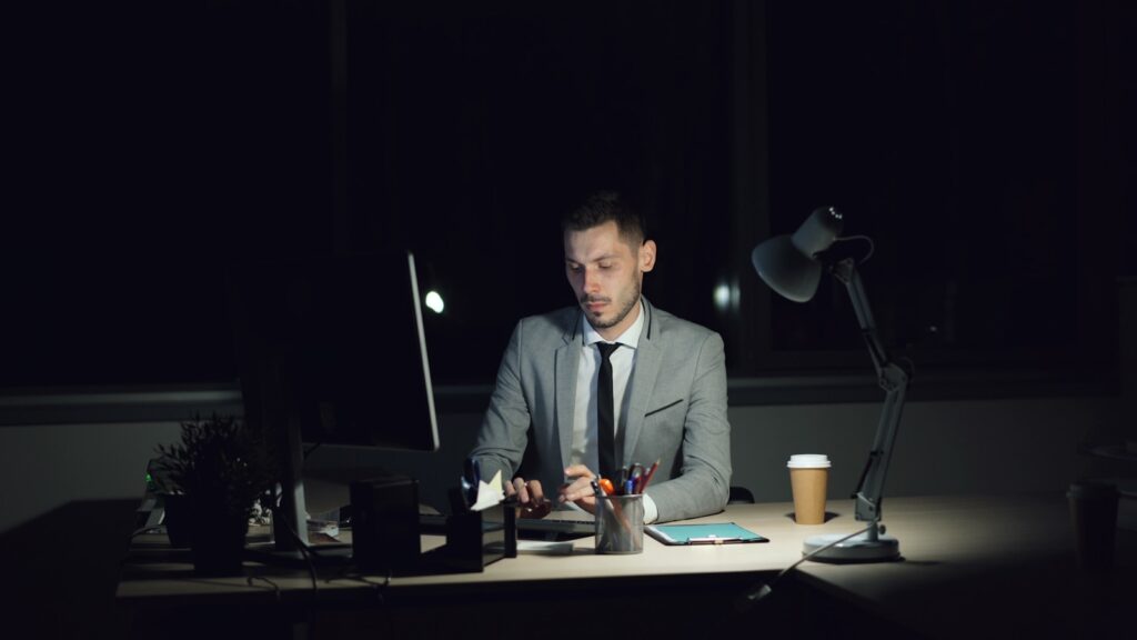 Man working late at his desk with coffee.