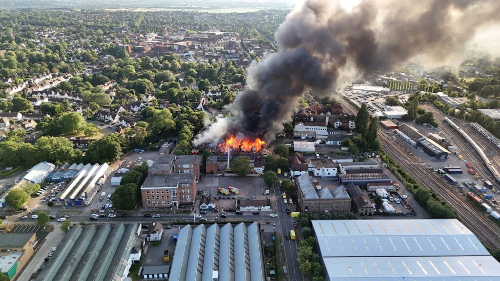 A large fire engulfs a building, releasing smoke.