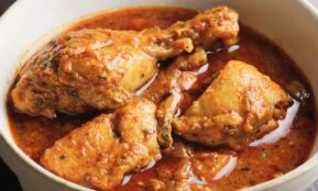 Chicken curry in a white bowl with sauce.