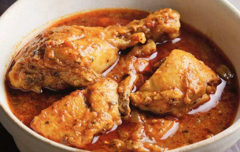 Chicken curry in a white bowl with sauce.