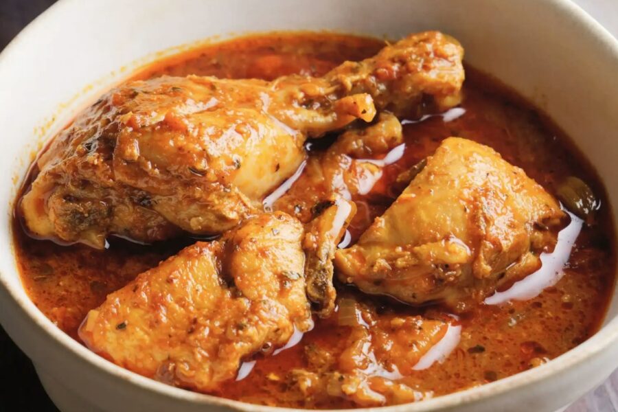 Chicken curry in a white bowl with sauce.
