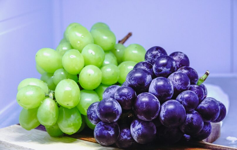 a bunch of grapes sitting on top of a cutting board