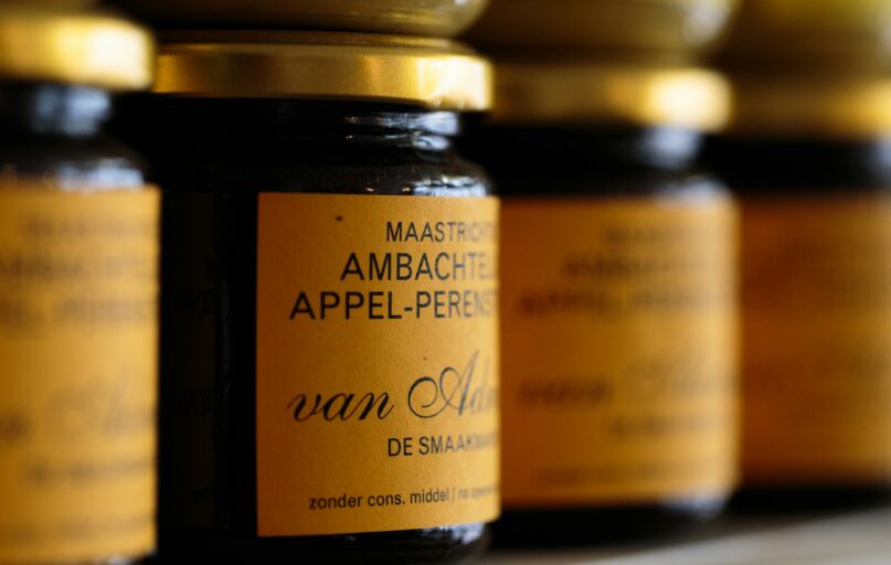 a row of jars filled with jam sitting on top of a shelf