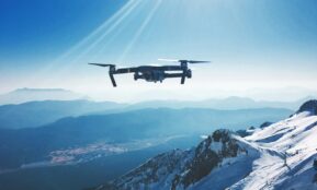 white quadcopter drone flying near snow mountain during daytime