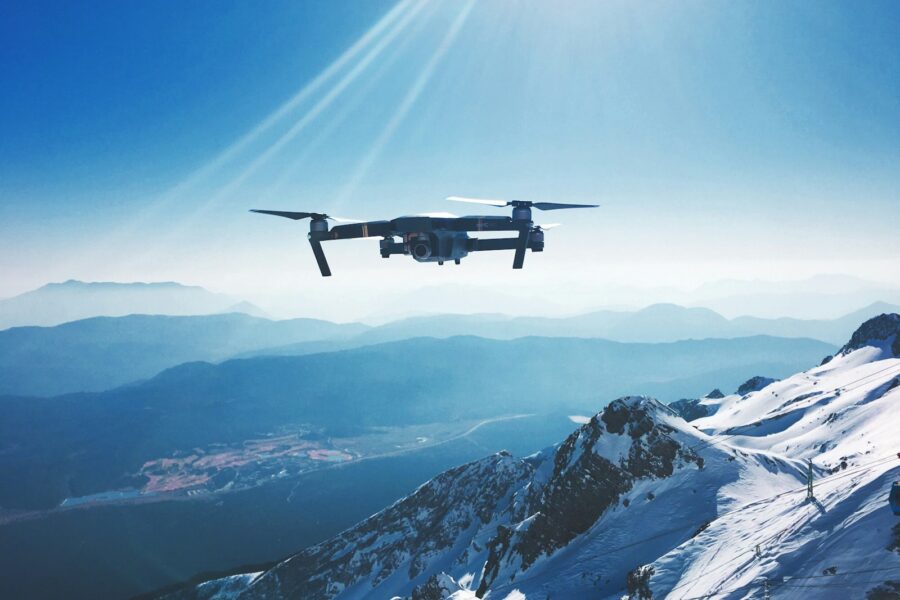 white quadcopter drone flying near snow mountain during daytime