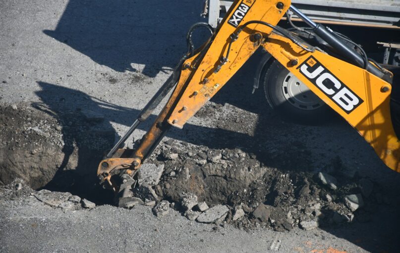 Yellow excavator digging in the dirt