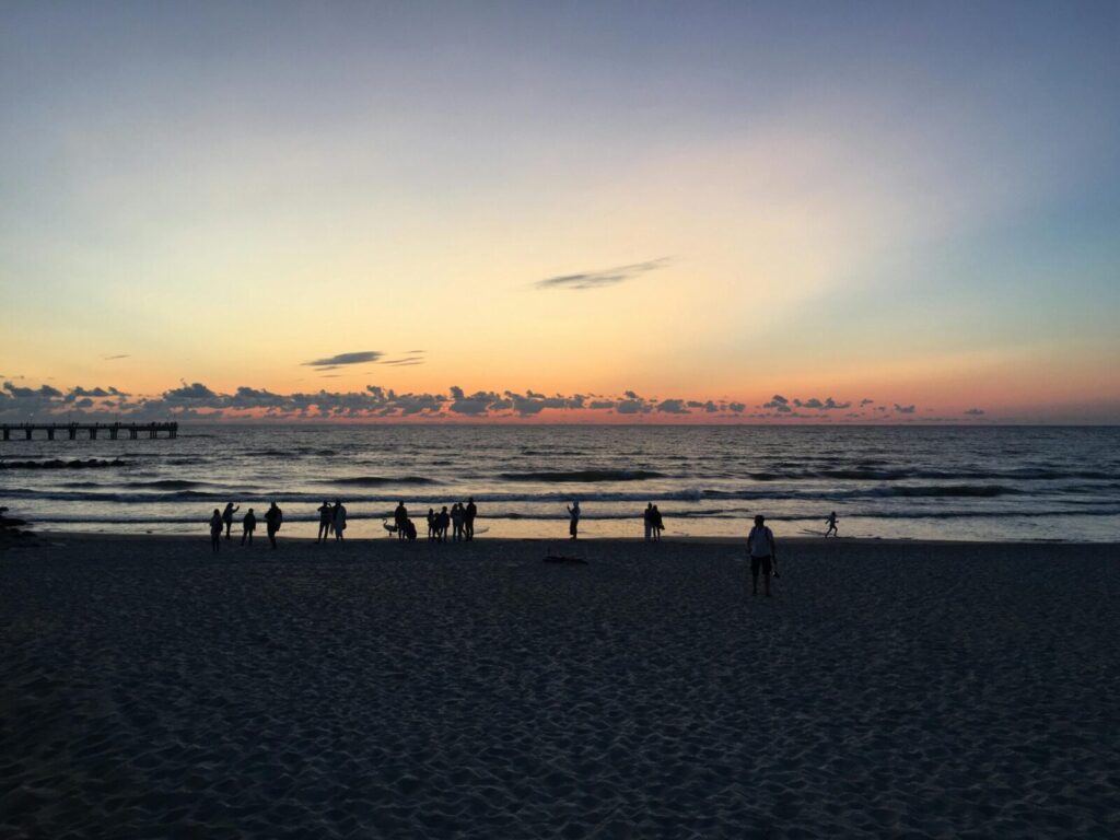 A serene sunset view at Palanga beach, Lithuania, with silhouettes of people enjoying the evening.
