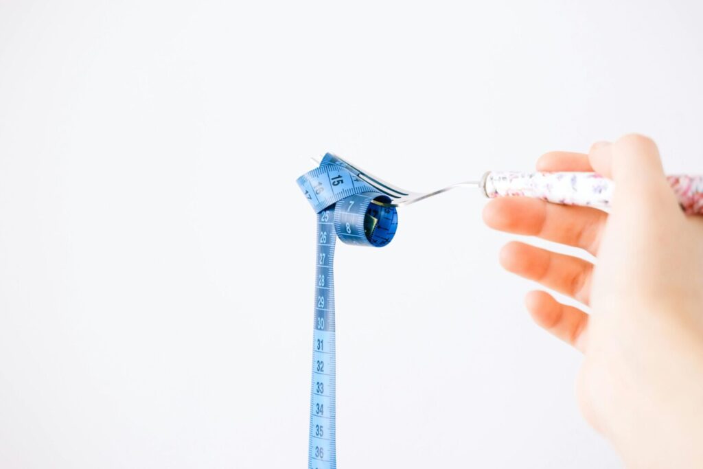 A blue measuring tape wrapped around a fork representing dieting or healthy eating concept.