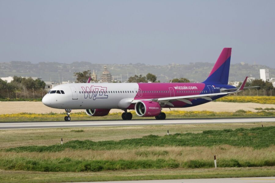 A Wizz Air Airbus A321 airplane taxis on the runway with a landscape background.