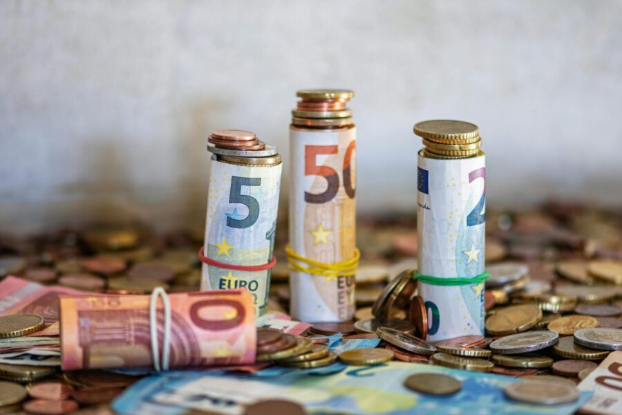 Close-up of rolled Euro banknotes and coins on a table, symbolizing finance and savings.