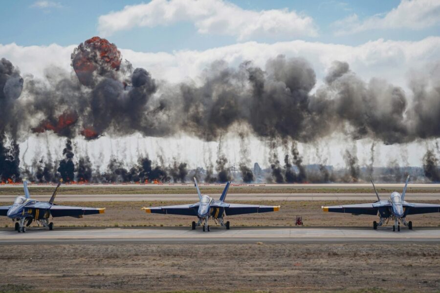 Dynamic scene featuring Blue Angels jets amid smoke and explosions during an airshow demonstration.