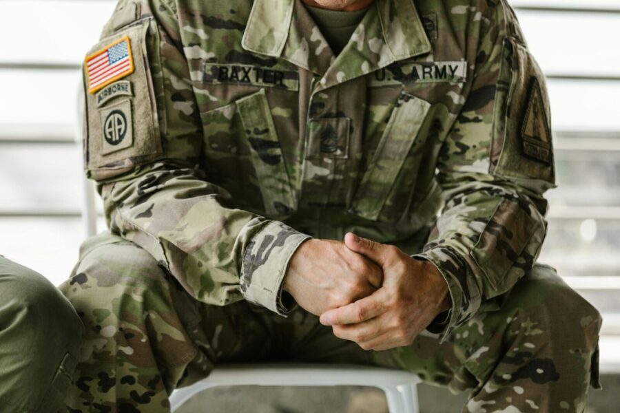 Close-up image of a soldier wearing a camouflage military uniform, displaying patches and insignia.