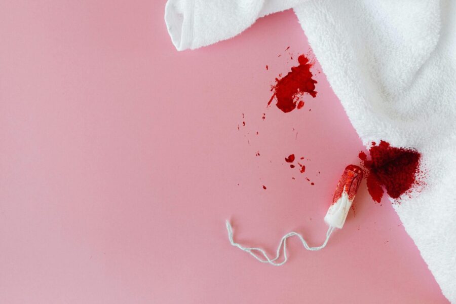Tampon with blood stain on pink background highlighting menstrual hygiene.