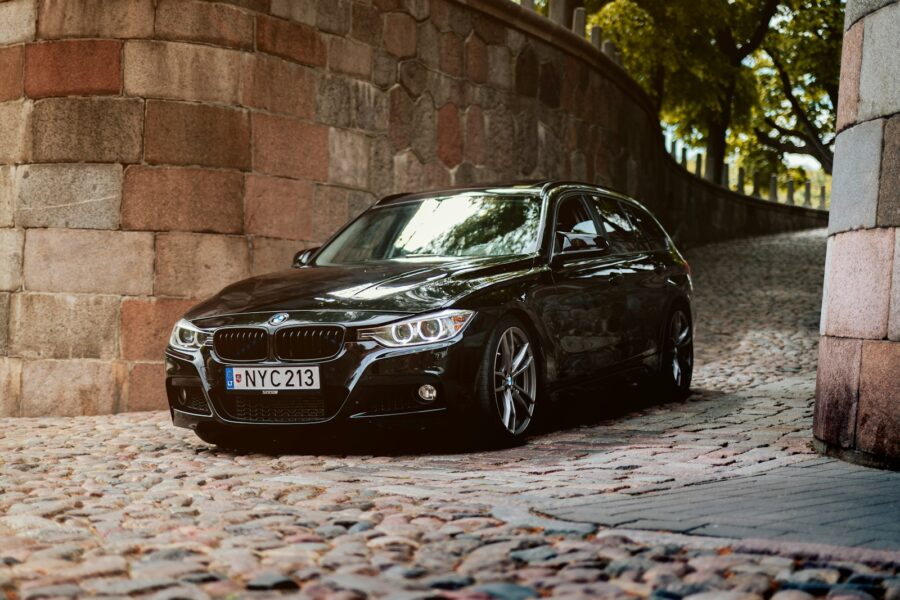 A black BMW is parked on cobblestone.