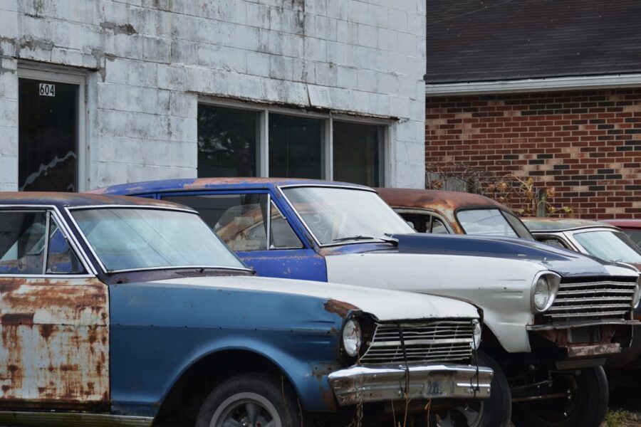 Row of old rusty cars parked outside building