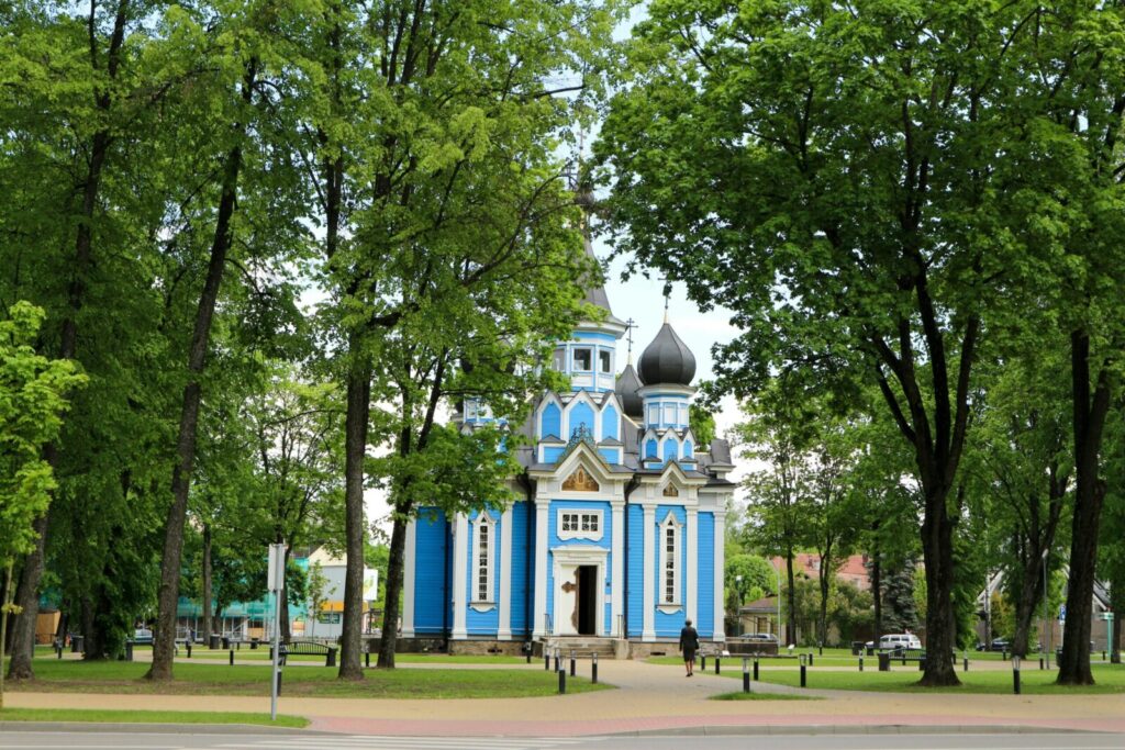 Stunning wooden Orthodox church amidst lush greenery in Druskininkai, Lithuania.