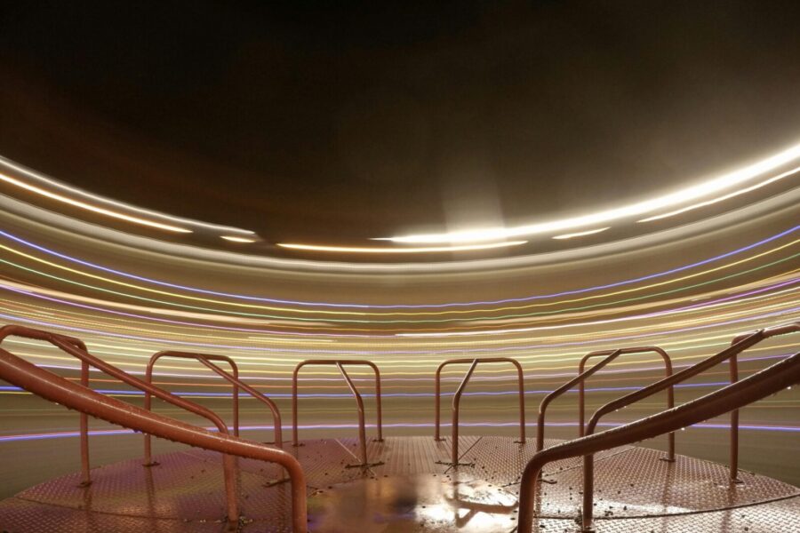 Dramatic long exposure of a carousel at night, creating vibrant light trails.